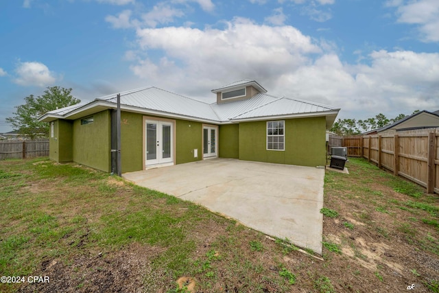 rear view of property featuring a lawn, french doors, and a patio