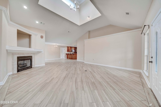 unfurnished living room featuring a tiled fireplace, light hardwood / wood-style flooring, and vaulted ceiling