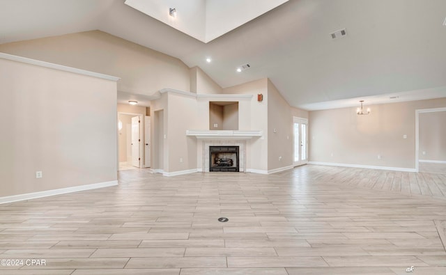 unfurnished living room featuring a tiled fireplace, light hardwood / wood-style flooring, high vaulted ceiling, and an inviting chandelier