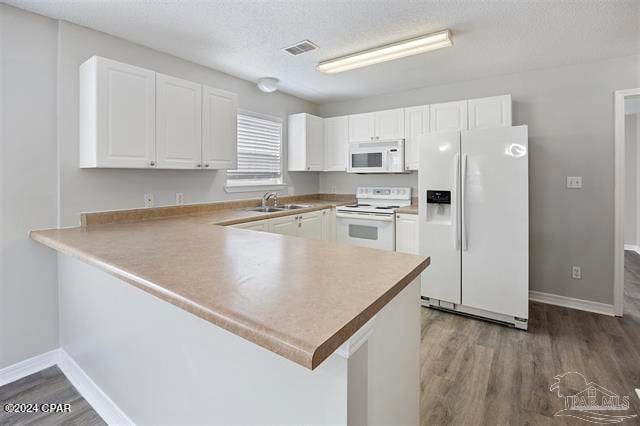 kitchen featuring kitchen peninsula, dark hardwood / wood-style flooring, white appliances, sink, and white cabinetry