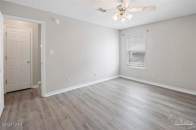 spare room featuring ceiling fan, a textured ceiling, and light wood-type flooring