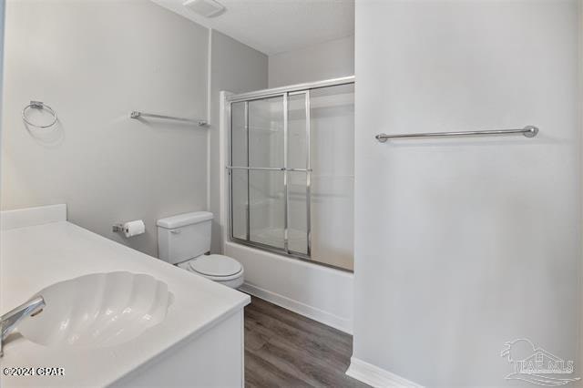 full bathroom featuring enclosed tub / shower combo, vanity, wood-type flooring, and toilet