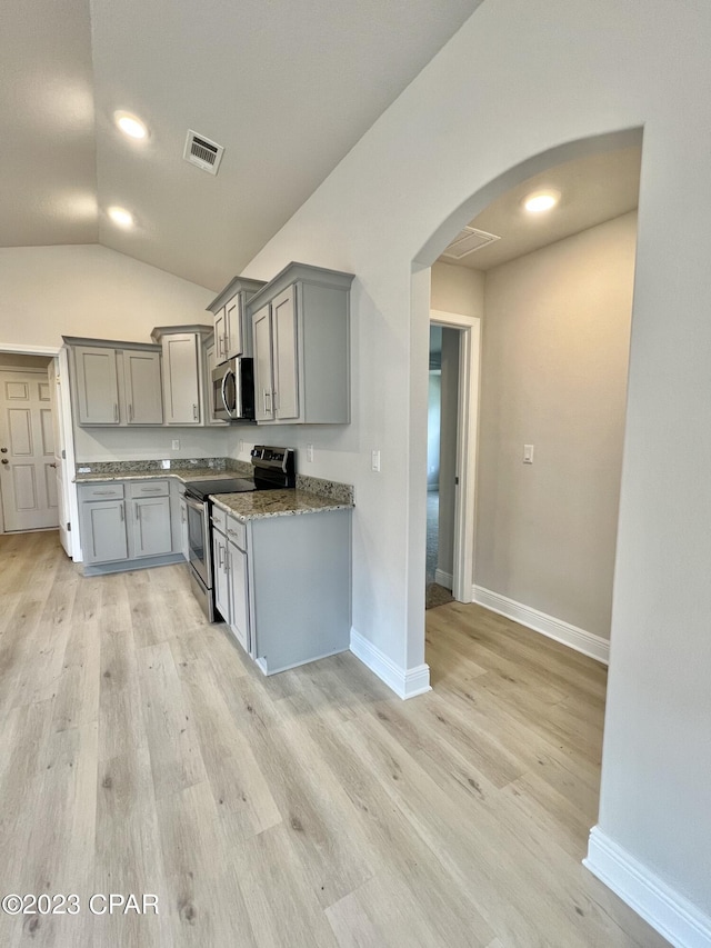 1202 Primrose Ln, Panama City, FL 32404 - kitchen featuring appliances with stainless steel finishes, gray cabinetry, arched walkways, vaulted ceiling, and light wood-style flooring