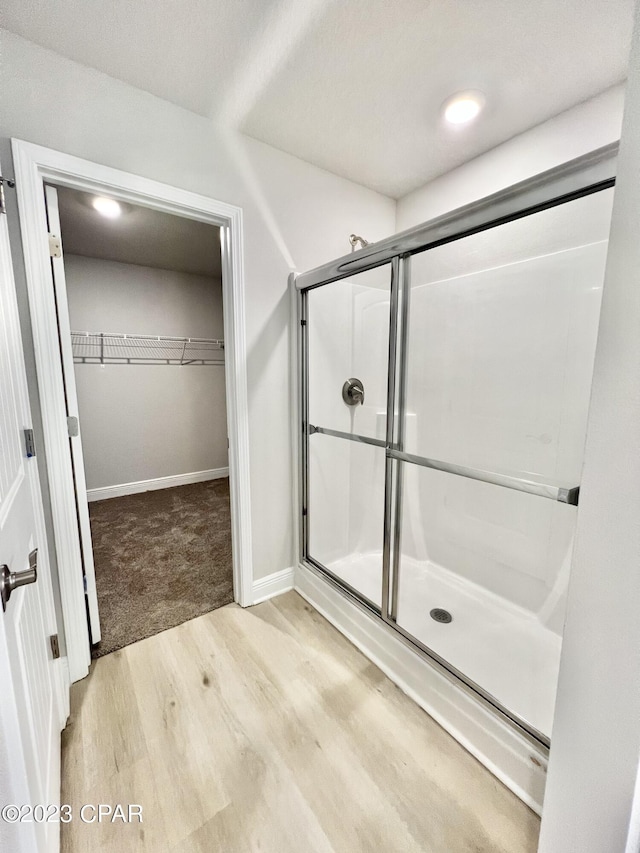 1202 Primrose Ln, Panama City, FL 32404 - full bathroom with wood finished floors, a walk in closet, a shower stall, and baseboards