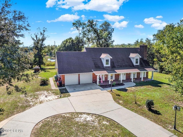 cape cod house featuring a garage, brick siding, driveway, a chimney, and a front yard