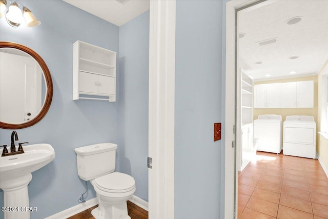 bathroom featuring tile patterned floors, toilet, baseboards, and separate washer and dryer