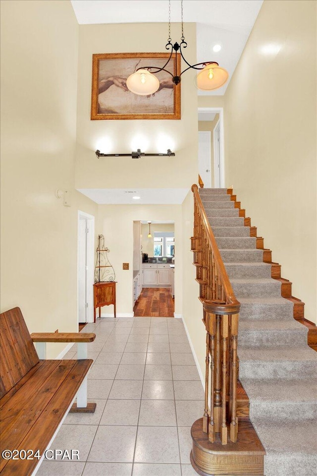 tiled foyer featuring stairway, a towering ceiling, and baseboards