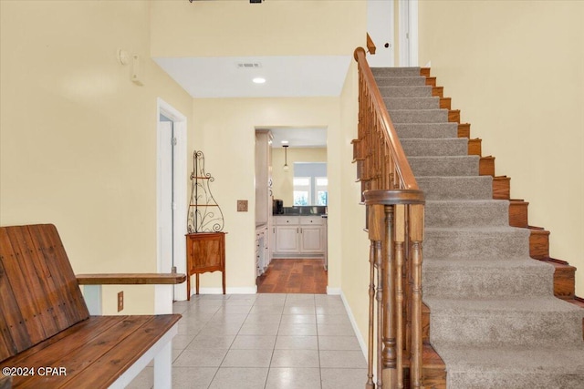 stairs featuring tile patterned flooring, visible vents, and baseboards