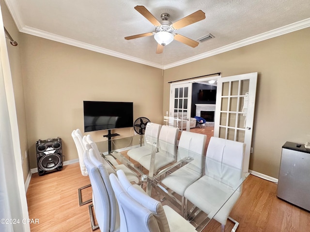 dining space with french doors, light wood-type flooring, ornamental molding, a textured ceiling, and ceiling fan