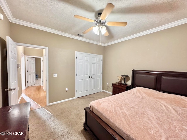 carpeted bedroom with a textured ceiling, a closet, ceiling fan, and crown molding