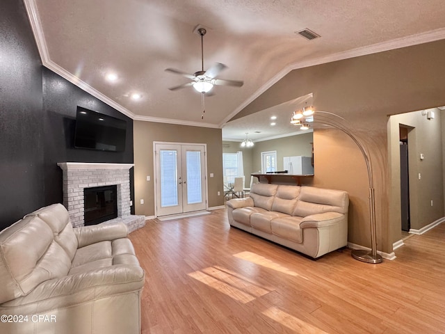 living room featuring a brick fireplace, vaulted ceiling, light hardwood / wood-style flooring, and crown molding