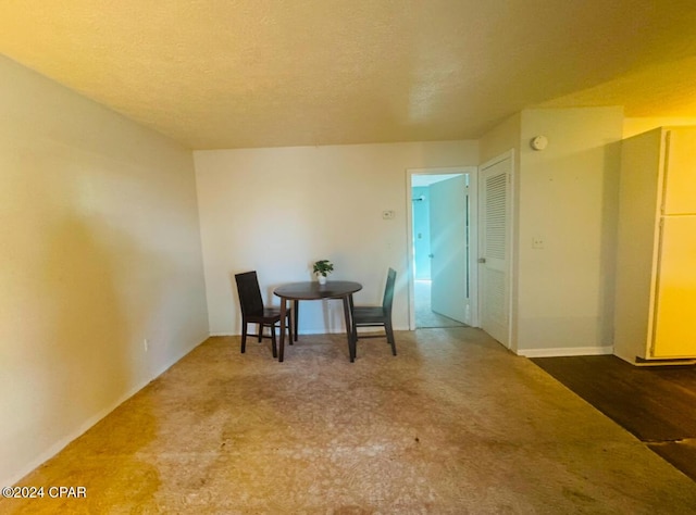 carpeted dining area with a textured ceiling