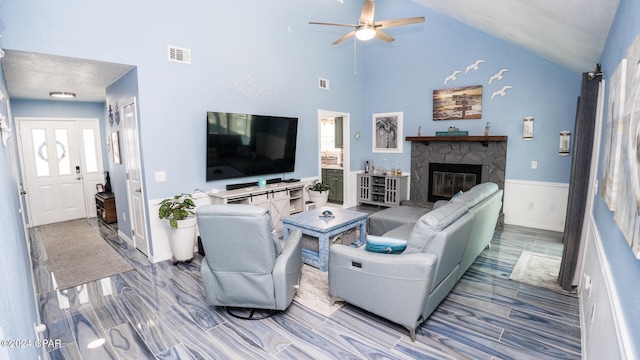 living room featuring a stone fireplace, ceiling fan, high vaulted ceiling, and wood-type flooring