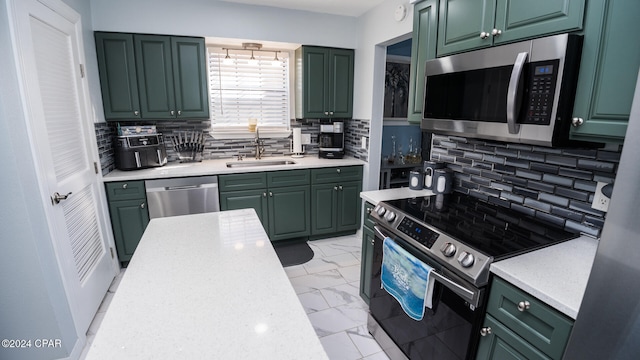 kitchen featuring decorative backsplash, appliances with stainless steel finishes, green cabinetry, and sink