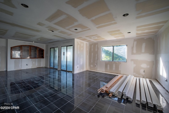 spare room featuring elevator and dark tile patterned flooring