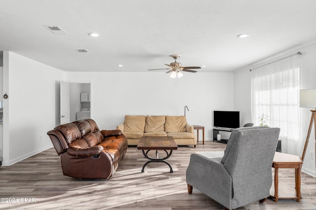 living room with hardwood / wood-style floors, ceiling fan, and washer / dryer