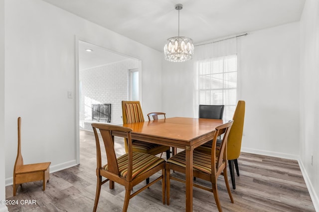dining area with a fireplace, hardwood / wood-style flooring, and a notable chandelier