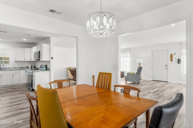dining space featuring an inviting chandelier, light hardwood / wood-style flooring, and a healthy amount of sunlight