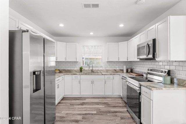 kitchen featuring white cabinets, stainless steel appliances, light hardwood / wood-style flooring, and sink