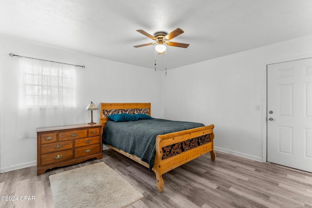 bedroom featuring ceiling fan, light hardwood / wood-style floors, and a textured ceiling
