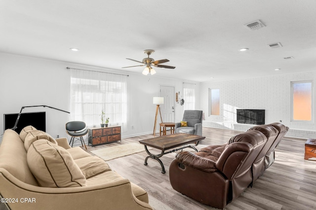 living room with a fireplace, ceiling fan, and light hardwood / wood-style flooring