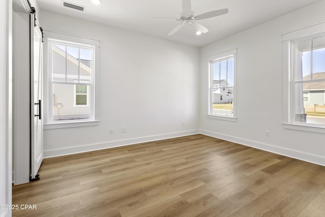 unfurnished room with light wood-type flooring, visible vents, ceiling fan, and baseboards