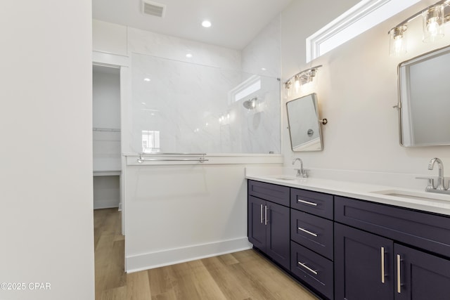 bathroom featuring visible vents, a walk in shower, a sink, and wood finished floors