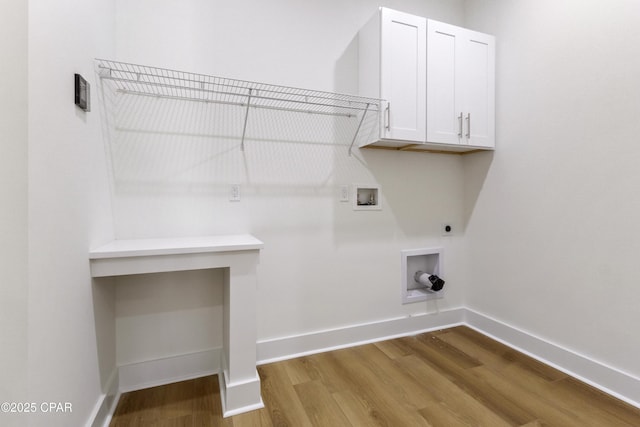 clothes washing area featuring cabinet space, baseboards, wood finished floors, washer hookup, and electric dryer hookup