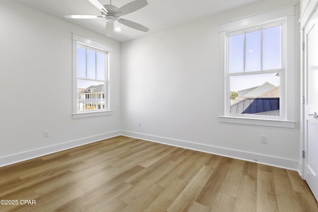 empty room featuring light wood finished floors, baseboards, and a wealth of natural light