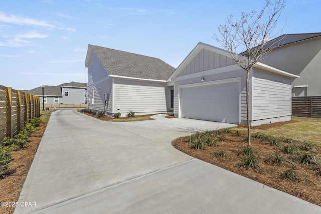 exterior space with driveway, board and batten siding, an attached garage, and fence