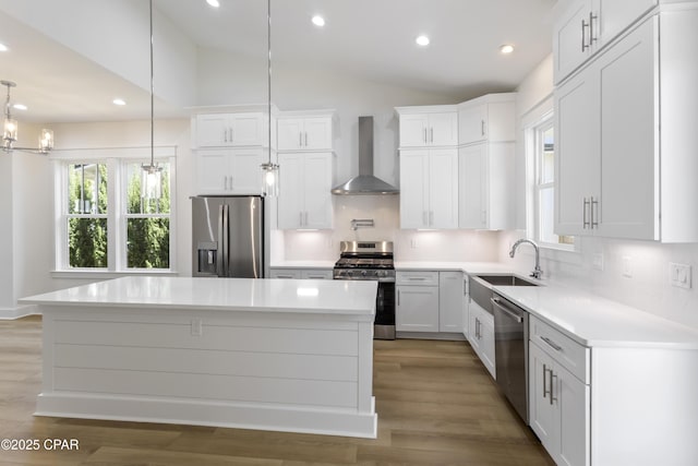 kitchen with stainless steel appliances, a sink, vaulted ceiling, wall chimney range hood, and decorative backsplash