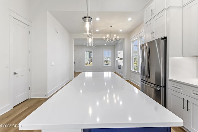 kitchen with a center island, stainless steel refrigerator with ice dispenser, recessed lighting, light countertops, and light wood-type flooring