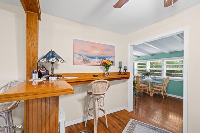 home office with ceiling fan, beamed ceiling, and hardwood / wood-style flooring