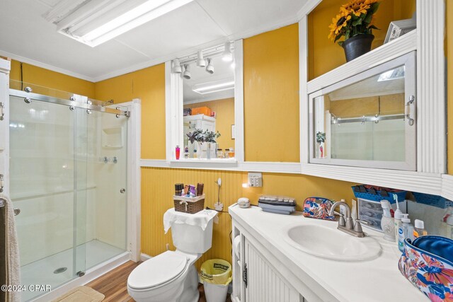 bathroom featuring walk in shower, crown molding, wood-type flooring, toilet, and vanity