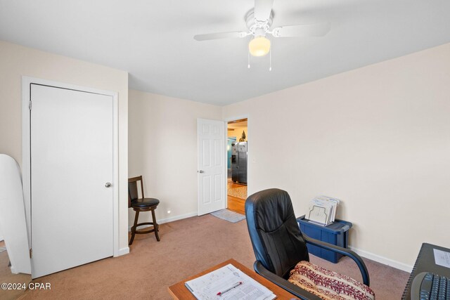 carpeted office space featuring ceiling fan