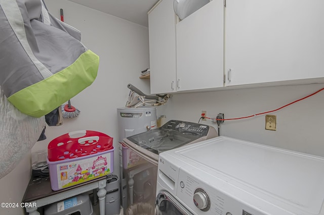 clothes washing area featuring cabinets, water heater, and separate washer and dryer