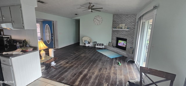 living room featuring vaulted ceiling, a brick fireplace, ceiling fan, and wood-type flooring