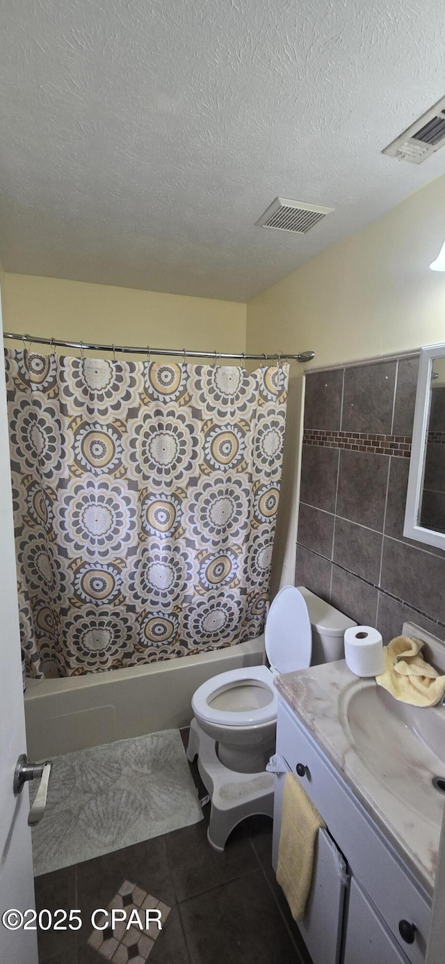 full bathroom with tile patterned flooring, toilet, tile walls, a textured ceiling, and vanity