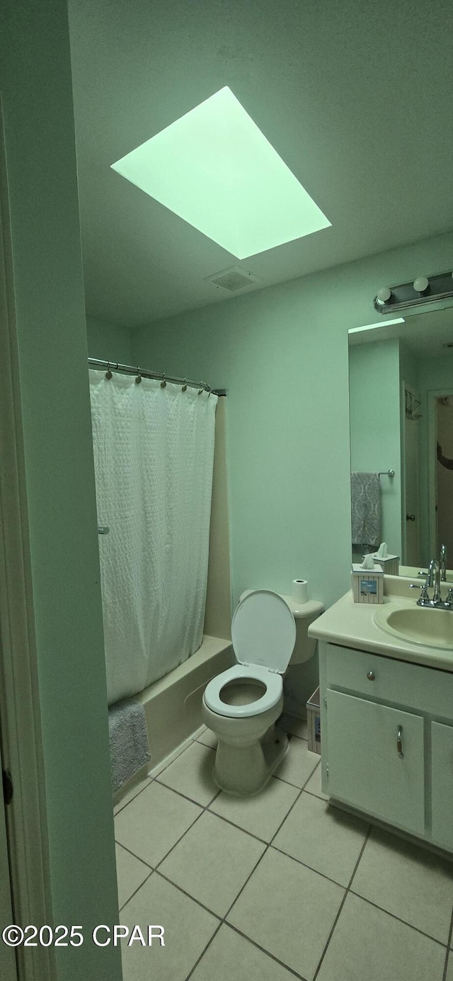 full bathroom featuring tile patterned floors, shower / bath combo with shower curtain, a skylight, and vanity