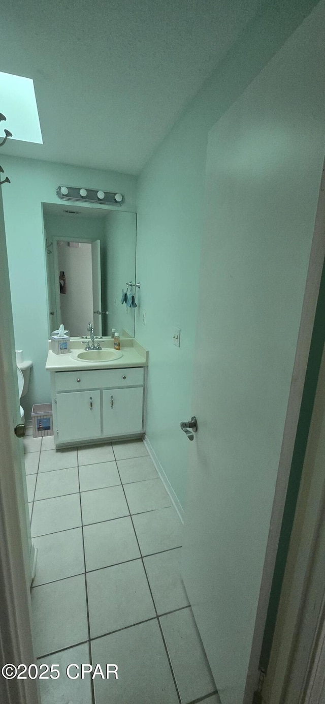 bathroom with toilet, tile patterned floors, a skylight, and vanity