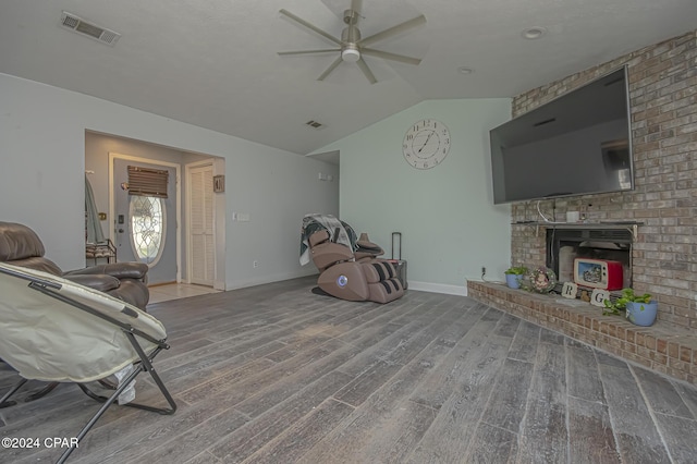 living room with hardwood / wood-style floors, lofted ceiling, ceiling fan, and a brick fireplace