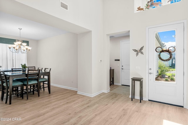 entryway with light hardwood / wood-style floors and a notable chandelier