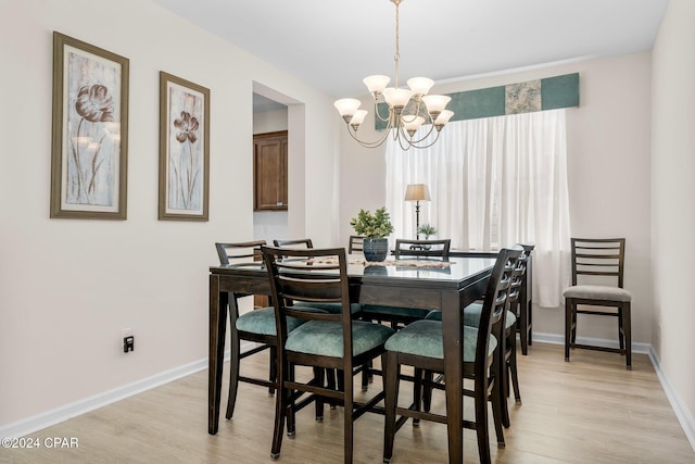 dining space featuring light hardwood / wood-style flooring and an inviting chandelier