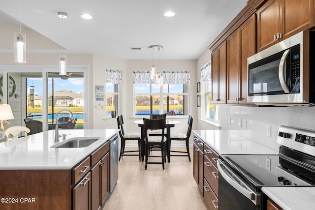 kitchen featuring decorative light fixtures, light hardwood / wood-style floors, sink, and appliances with stainless steel finishes