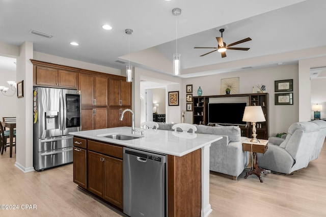 kitchen with light hardwood / wood-style floors, sink, an island with sink, and appliances with stainless steel finishes