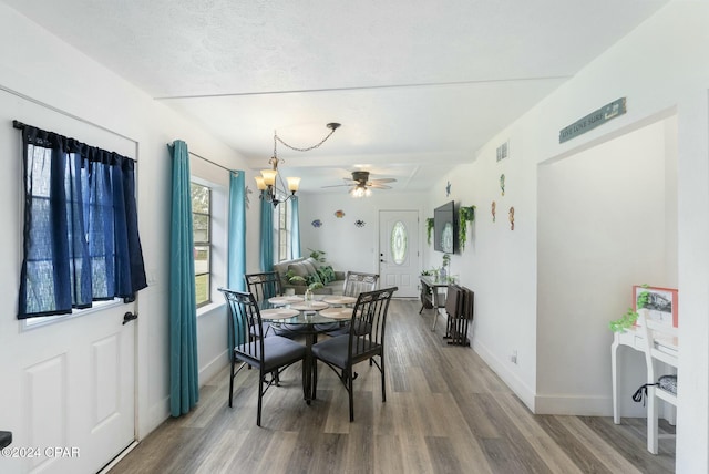 dining space with a textured ceiling, hardwood / wood-style floors, and ceiling fan with notable chandelier