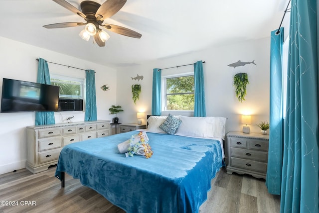 bedroom featuring ceiling fan, light wood-type flooring, and multiple windows