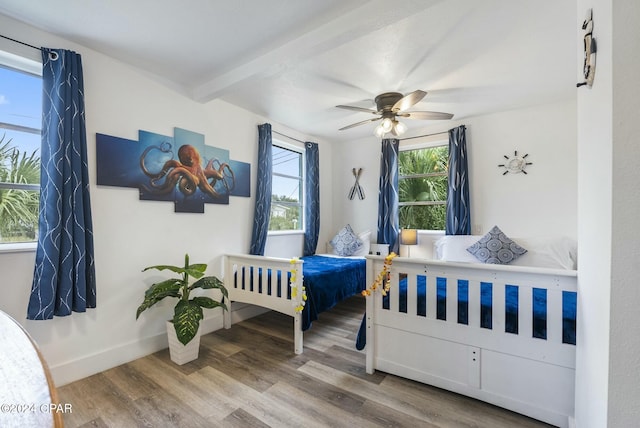 bedroom with ceiling fan, beamed ceiling, and wood-type flooring