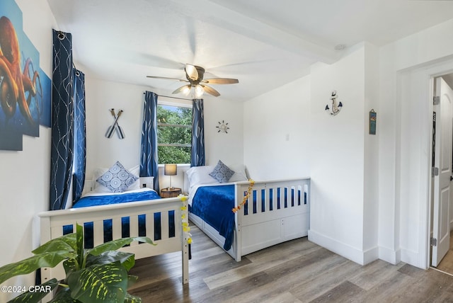 bedroom with hardwood / wood-style floors, ceiling fan, and beam ceiling