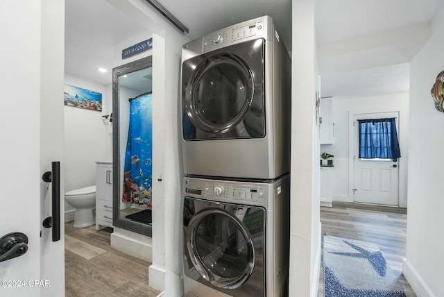 laundry room featuring stacked washing maching and dryer and light wood-type flooring